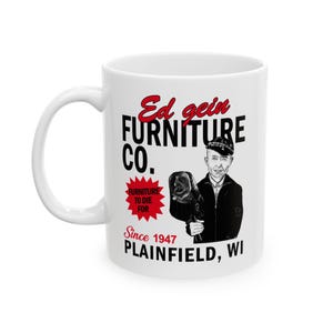 May include: White ceramic mug featuring the text "Ed Gein Furniture Co." in black and red, with an illustration of a man and a head. The mug also includes the text "Furniture to Die For" and "Since 1947 Plainfield, WI."
