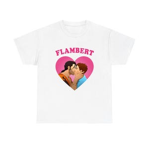 May include: White t-shirt featuring a pink heart with two men kissing. The word "FLAMBERT" is arched above the heart. The men are depicted with dark hair and wearing orange and blue shirts.
