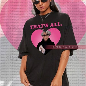 Könnte beinhalten: Schwarzes Unisex-T-Shirt mit dem Text "THAT'S ALL." über einer rosa Herzgrafik. Das Herz enthält ein Bild einer Frau mit Sonnenbrille. Das Shirt ist übergroß.