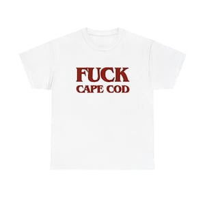 May include: A white short-sleeved t-shirt featuring the text FUCK CAPE COD printed in a bold, dark red serif font across the center of the chest. The garment has a standard crew neckline and a simple, clean design with no other visible patterns.