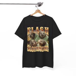 Puede incluir: Camiseta negra con un diseño retro dorado de cuatro perezosos y el texto "FLASH SLOTHMORE". Los perezosos llevan camisas verdes. El diseño está centrado en la parte delantera de la camiseta.