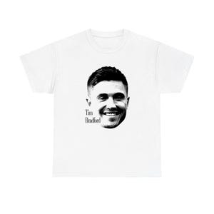 May include: A white short-sleeved t-shirt featuring a black and white graphic print of a smiling person's face centred on the chest. The text "Tim Bradford" is printed in black lettering directly below the chin of the portrait.