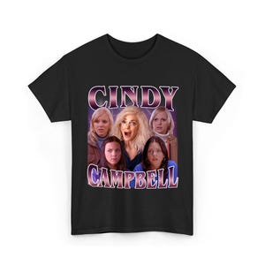Könnte beinhalten: Schwarzes T-Shirt mit einer Grafik von sechs Frauen und dem Text "CINDY CAMPBELL" in Lila und Weiß. Die Frauen haben überraschte Ausdrücke. Das T-Shirt hat einen Rundhalsausschnitt und kurze Ärmel.