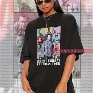 May include: Black unisex t-shirt featuring a colorful graphic of Jeremy Usborne from the TV show "Peep Show" with the text "JEREMY USBORNE THE ERAS TOUR". The shirt is oversized and has a crew neck.