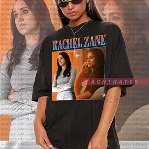 May include: Black unisex t-shirt featuring a graphic of Rachel Zane with the text "RACHEL ZANE" in a retro font. The shirt has a crew neck and short sleeves. The model is wearing a 2XL shirt.