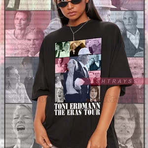 May include: Black unisex t-shirt featuring a collage of images and the text "TONI ERDMANN THE ERAS TOUR." The shirt is worn by a person wearing sunglasses. The background has a repeating pattern of faces.