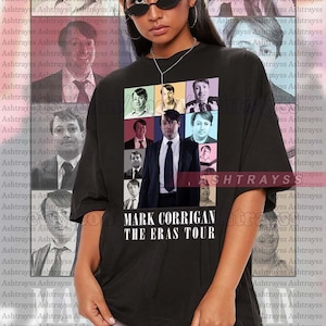Peut inclure: T-shirt noir avec un collage d'images et le texte "MARK CORRIGAN THE ERAS TOUR". Le t-shirt est porté par une personne portant des lunettes de soleil. Le fond présente un motif répété du mot "Ashtrayss".
