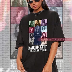 Puede incluir: Camiseta negra unisex con una cuadrícula de imágenes de una mujer, con el texto "KATE BECKETT THE ERAS TOUR" en blanco. La modelo lleva la camiseta y gafas de sol. La camiseta es de gran tamaño.