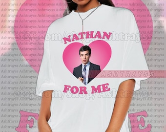 May include: White t-shirt featuring a pink heart graphic with the text "NATHAN" and a photo of a man in a suit. Below the heart, the text reads "FOR ME".