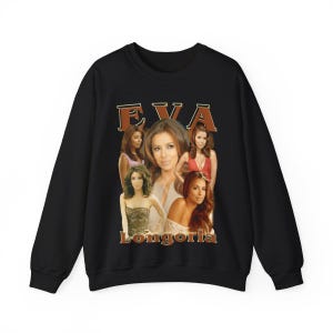 Puede incluir: Sudadera negra con cuello redondo con un collage de imágenes de Eva Longoria. La palabra "EVA" está impresa en marrón, en una fuente de estilo vintage encima de las imágenes. El nombre "Longoria" está impreso debajo de las imágenes en una fuente similar.
