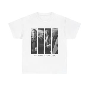 Puede incluir: Una camiseta blanca de manga corta con un estampado gráfico en blanco y negro de cuatro paneles verticales, cada uno con un retrato diferente del personaje Haymitch Abernathy. El texto HAYMITCH ABERNATHY está impreso en negro bajo los paneles.