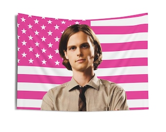 May include: A rectangular wall tapestry featuring a portrait of a person with brown hair, wearing a tan patterned button-down shirt and a dark tie, set against a background of a pink and white American flag with stars and horizontal stripes.
