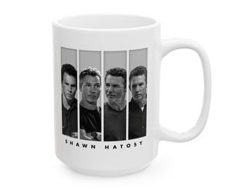 May include: A white ceramic mug featuring a black and white graphic print of four distinct portraits of the actor Shawn Hatosy arranged in vertical panels. The name SHAWN HATOSY is printed in black capital letters centered below the portrait panels.