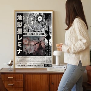 Könnte beinhalten: Ein gerahmtes Poster mit dem Titel "HELLSTAR REMINA" in englischer und japanischer Schrift. Das Kunstwerk zeigt eine detaillierte Schwarz-Weiß-Illustration eines Himmelskörpers und einer Figur. Das Poster wird auf einem Holzschrank ausgestellt.