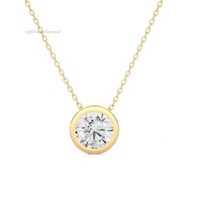 May include: A gold-colored necklace with a round, clear diamond pendant. The diamond is set in a bezel setting. The chain is delicate and gold-colored. The text "LightGrownDiamond" is visible in the upper left corner.