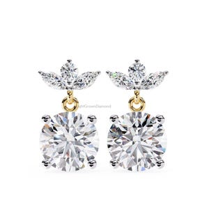 May include: A pair of diamond earrings with a floral design. Each earring features a large, round, brilliant-cut diamond suspended from a smaller cluster of marquise-cut diamonds. The earrings have gold-coloured settings and are set against a white background.