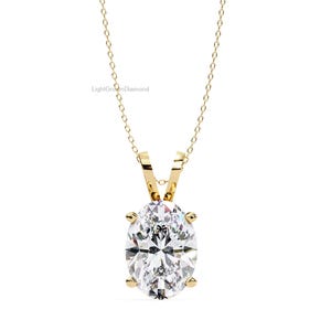 May include: A gold-colored necklace with a large, oval-cut diamond pendant. The diamond is set in a four-prong setting and hangs from a delicate chain. The text "LightGrownDiamond" is visible.