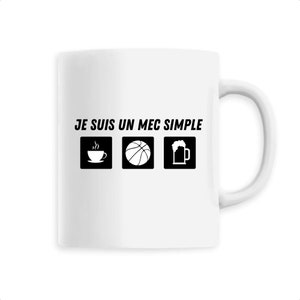 May include: White ceramic mug with the phrase "JE SUIS UN MEC SIMPLE" in black text. The mug features three black icons: a steaming coffee cup, a basketball, and a beer mug.