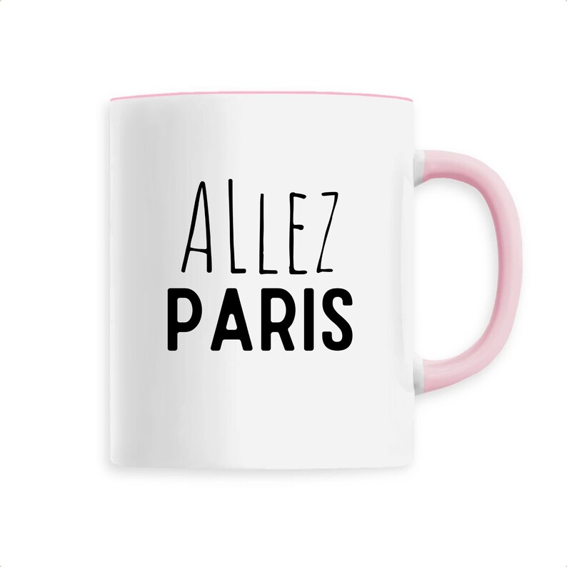 May include: White ceramic mug with a pink interior and handle. The mug features the words "ALLEZ PARIS" in black, handwritten-style lettering. A simple and stylish design.