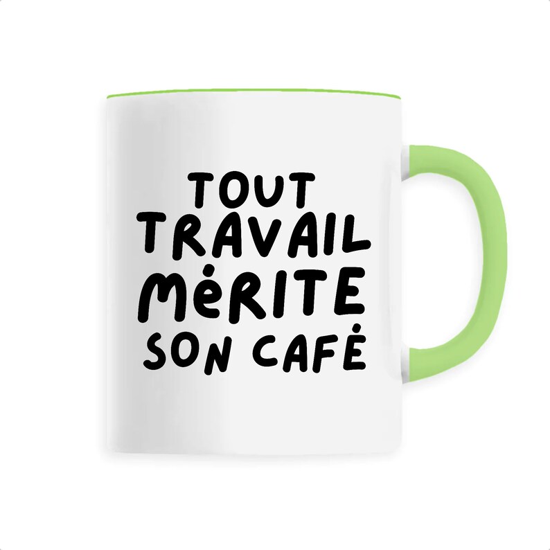 Peut inclure: Mug en c&eacute;ramique blanche avec une anse et un bord verts. Le mug porte l'inscription en noir "TOUT TRAVAIL M&Eacute;RITE SON CAF&Eacute;", une phrase qui signifie "Tout travail m&eacute;rite son caf&eacute;".
