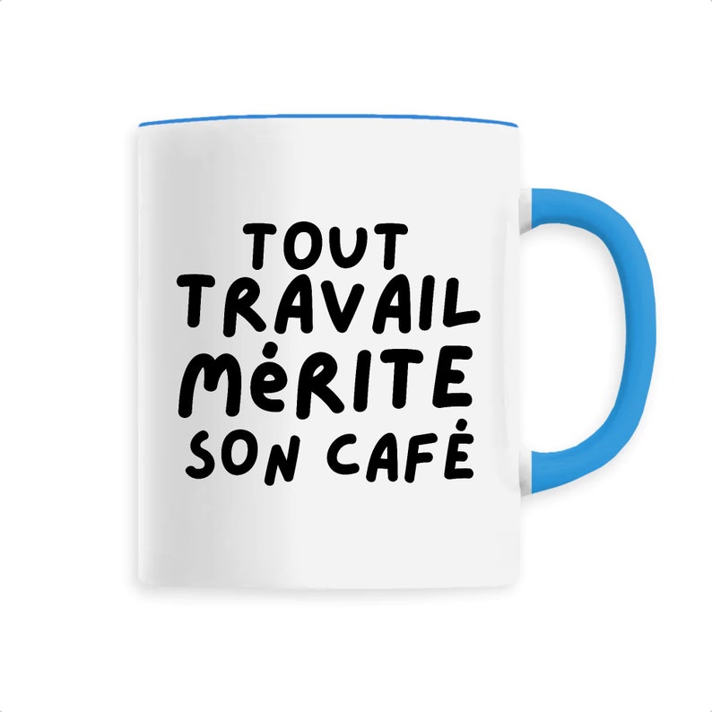 Peut inclure: Tasse &agrave; caf&eacute; en c&eacute;ramique blanche avec une anse et un bord bleus. La tasse porte l'inscription noire "TOUT TRAVAIL M&Eacute;RITE SON CAF&Eacute;". Id&eacute;ale pour les boissons chaudes.