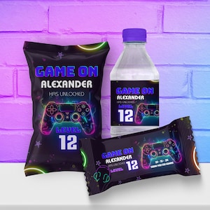 May include: A set of party favors for a video game themed party. The favors include a bag of chips, a bottle of water, and a candy bar. Each item has a label with a neon green and purple video game controller graphic and the text "Game On Alexander Has Unlocked Level 12".