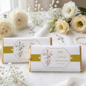 May include: Two white chocolate bars with gold foil wrapping. Each bar features a decorative label with a cross, flowers, and the word "Confirmation". The bars are surrounded by white flowers and religious jewelry.