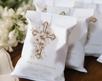 Könnte beinhalten: Weiße Gastgeschenktüten mit einem goldenen Kreuzdesign, floralen Akzenten und dem Text "First Holy Communion David James 28. Juli, 20xx." Die Tüten liegen auf einer Holzoberfläche, mit weißen Blumen im Hintergrund.