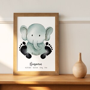 Peut inclure: Une impression encadrée à l'aquarelle représentant un éléphant bleu clair avec des empreintes de pieds noires. L'impression comprend le nom "Benjamin", la date, l'heure, le poids et la taille (51cm). Le cadre est en bois.