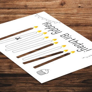 May include: A printable birthday card with a black and white illustration of candles, a cupcake, and a party hat. The text "Happy Birthday!" is written in black.