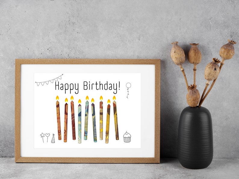 May include: A framed print with a white background and the text "Happy Birthday!" in black. The print features a row of 11 colorful candles with yellow flames.