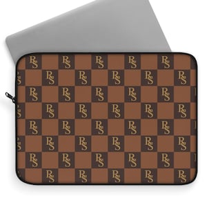 May include: A brown laptop sleeve with a repeating pattern of the letters "R" and "S" in a gold color, arranged in a checkerboard design. A silver laptop is partially visible behind the sleeve.