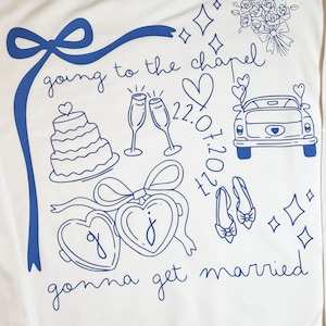 May include: White sweatshirt with blue line art. The design includes a bow, cake, champagne glasses, a car, hearts, shoes, and the phrases "going to the chapel" and "gonna get married".