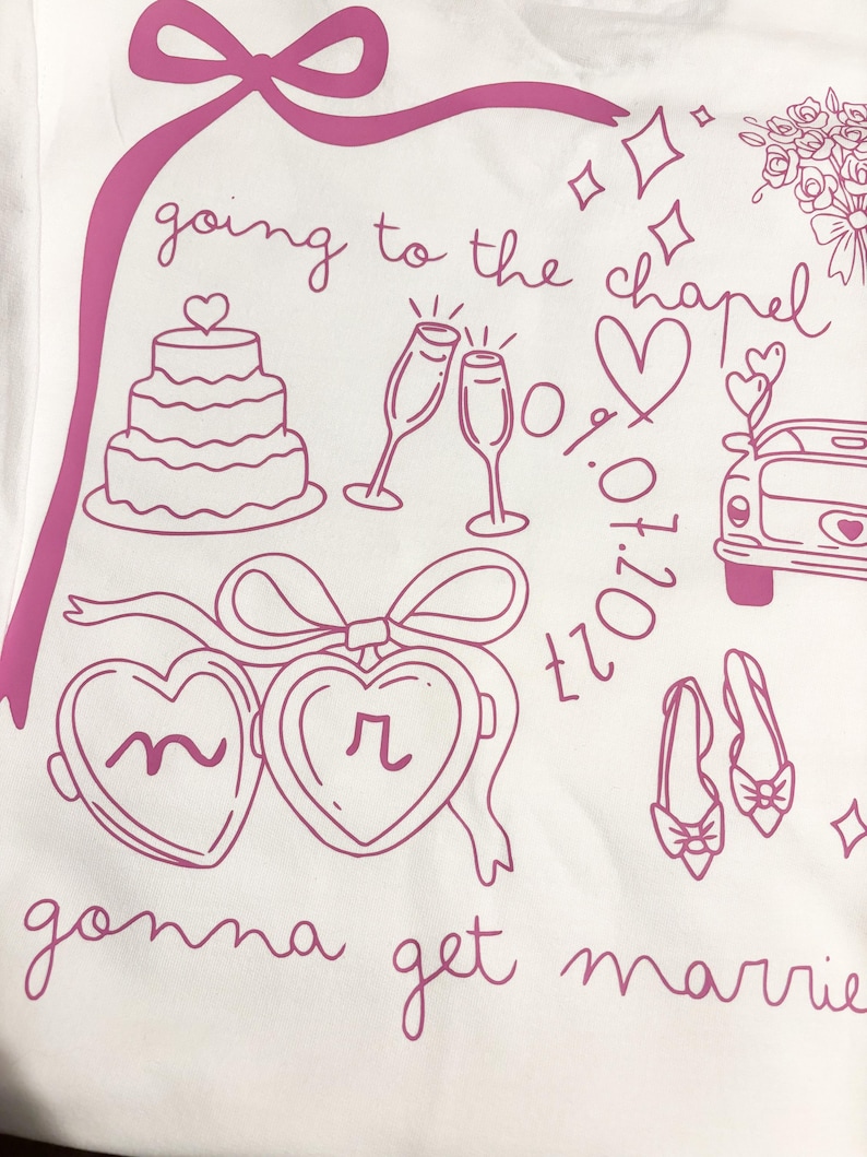 May include: White t-shirt with a pink illustration of wedding-related graphics. The design includes a cake, champagne glasses, hearts, a car, shoes, and the text "going to the chapel" and "gonna get married".