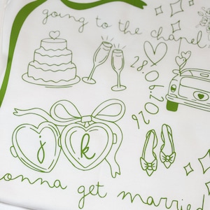May include: White fabric with green line art illustrations of wedding-themed elements. Includes a cake, champagne glasses, a car, hearts, shoes, and the text "going to the chapel" and "gonna get married".