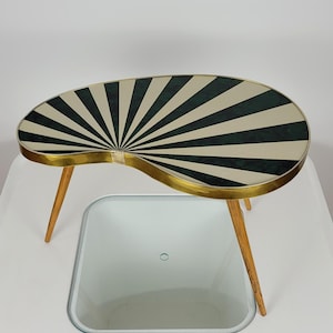 Può includere: Un tavolino da salotto in stile moderno di metà secolo con un piano unico a forma di rene. Il piano del tavolo è realizzato in laminato a strisce bianche e verdi con un bordo in ottone. Il tavolo ha tre gambe in legno.