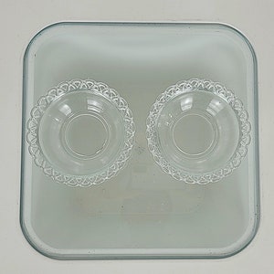 Pode incluir: Duas tigelas de vidro transparente com bordas decorativas estão dentro de um prato de vidro transparente para assar em uma superfície branca.