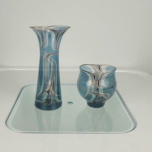 Könnte beinhalten: Ein Set aus drei Keramikbechern mit gesprenkelter, matter Oberfläche. Die Becher sind in Creme-, Hellgrau- und Dunkelgrautönen gehalten. Jeder Becher hat ein schlichtes, minimalistisches Design.