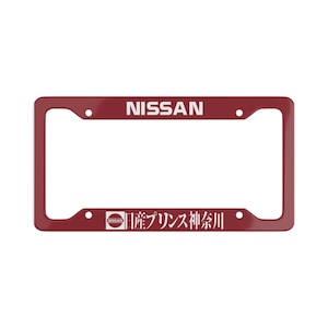 Könnte beinhalten: Ein burgunderfarbener Kennzeichenrahmen mit dem Wort "NISSAN" in Weiß oben. Der Rahmen hat unten japanischen Text und ein Nissan-Logo.