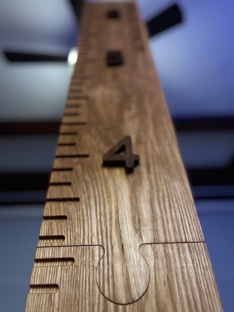 May include: A wooden growth chart ruler with the number 4 prominently displayed. The ruler is made of light-colored wood with a grain pattern. The chart has etched markings for measuring height. The word "INCHES" is visible.