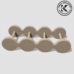 May include: A wooden wine rack with a unique design featuring rounded, connected sections. The rack is made of light brown wood and can hold six bottles of wine.