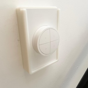 May include: A white wall-mounted remote control with four buttons. The remote control is circular and has a white plastic frame.
