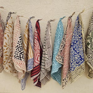 Könnte beinhalten: Eine Sammlung von zehn Stoffquadraten mit verschiedenen bunten Mustern und Designs. Die Quadrate sind aus einem hellen Stoff mit dunklen Mustern gefertigt. Die Muster umfassen florale, geometrische und abstrakte Designs.