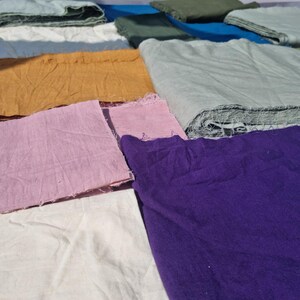 May include: Assortment of colorful fabric swatches in shades of yellow, pink, purple, green, and blue. The fabric pieces are arranged on a surface, showcasing various textures and hues. Ideal for textile projects.