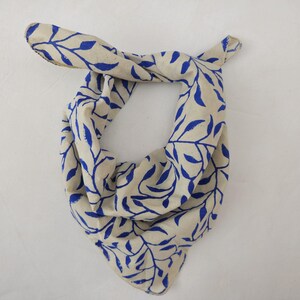 Könnte beinhalten: Ein weißes Bandana mit einem blauen Blatt-Muster. Das Bandana ist zu einem Dreieck gefaltet.