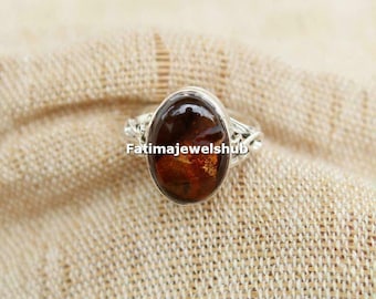 May include: A silver ring featuring a brown oval gemstone. The ring has a twisted wire design and the gemstone has a golden sheen.