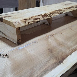 Peut inclure: Une grande table en bois à bord vif avec une finition en bois naturel. La table est dotée d'une étagère intégrée pour l'électronique. La table est fabriquée par Michigan Rustic Woodlands.