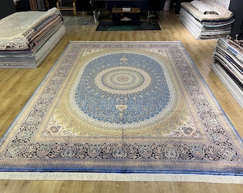 May include: A large, blue and cream colored rug with a detailed floral pattern. The rug has a central medallion with a smaller circle in the center. The rug has a fringe border.