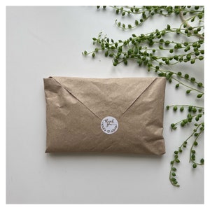May include: A brown paper package with a white circle sticker that says "Thank you" in cursive with a small heart below the text.
