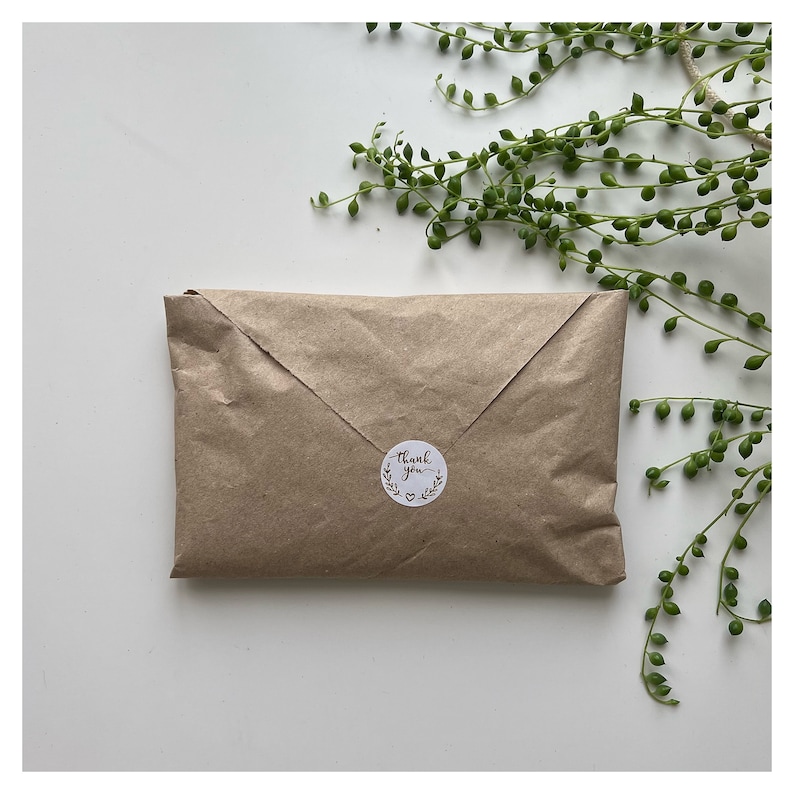May include: A brown paper package with a white circle sticker that says "Thank you" in cursive with a small heart below the text.